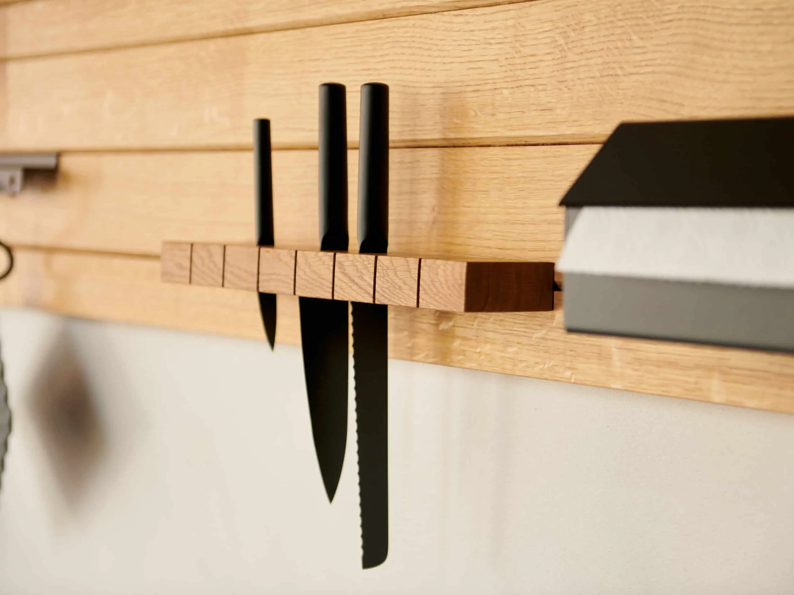 Nahaufnahme vom Küchenzubehör am TUUL Küchenboard. Ein Messerblock ist im Holzbrett eingehängt.