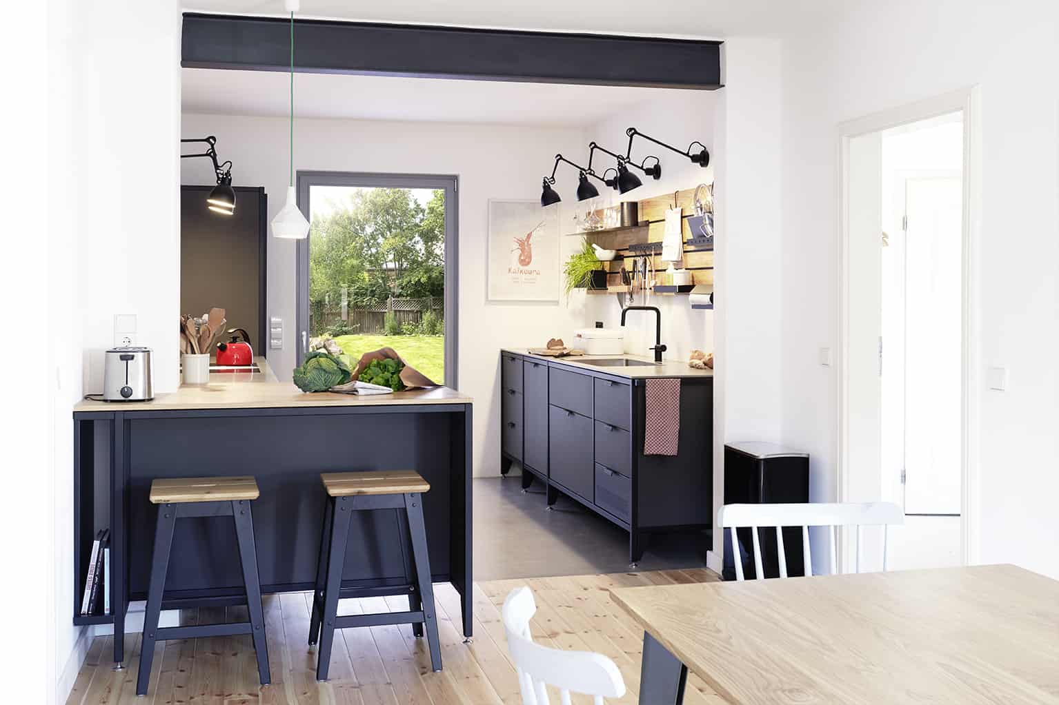 Gemütlicher Wohn- und Kochbereich mit einer dunklen Küche aus Linoleum und Stahl.
