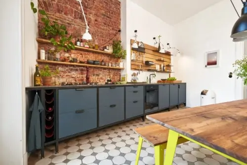 Moderner Küchenbereich einer Altbauwohnung. Eine Backsteinwand, sowie eine Modulküche aus Stahl und Linoleum verleihen dem Raum einen Industrial-Look.