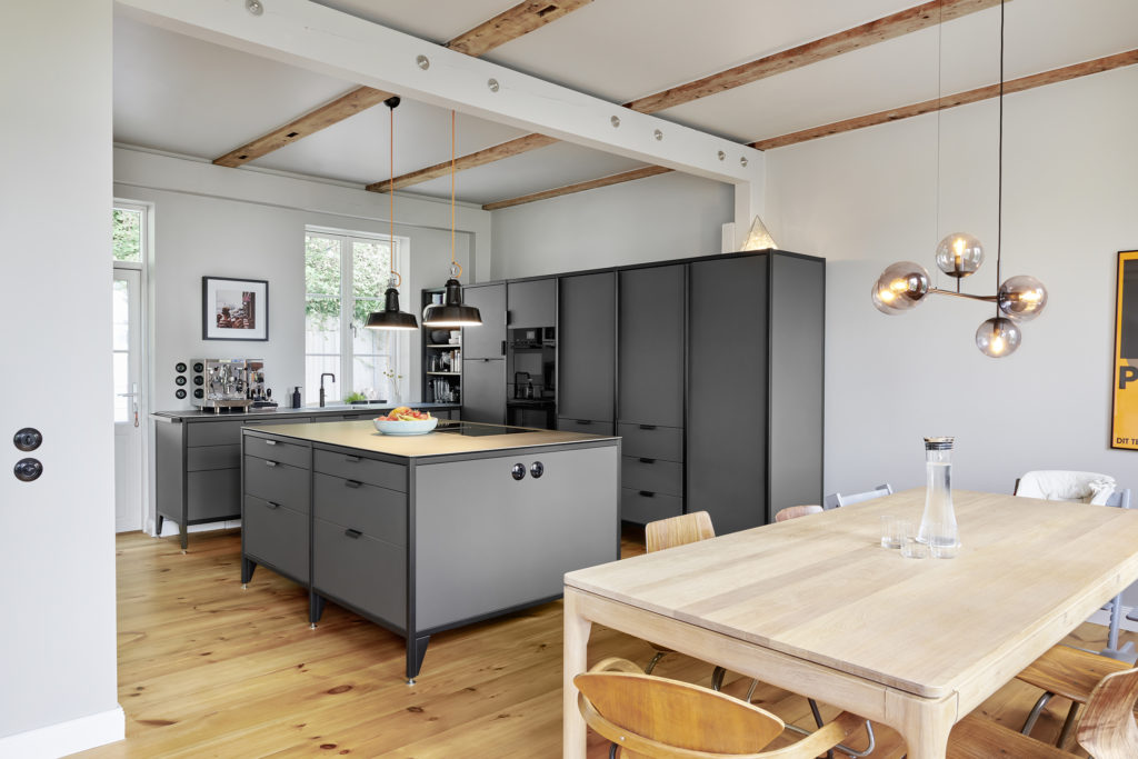Einblick in eine moderne Küche eines frisch saniertem Lofts. Eine Modulküche, sowie weitere Einrichtungselemente im zeitlosen Design, schmücken den Raum.