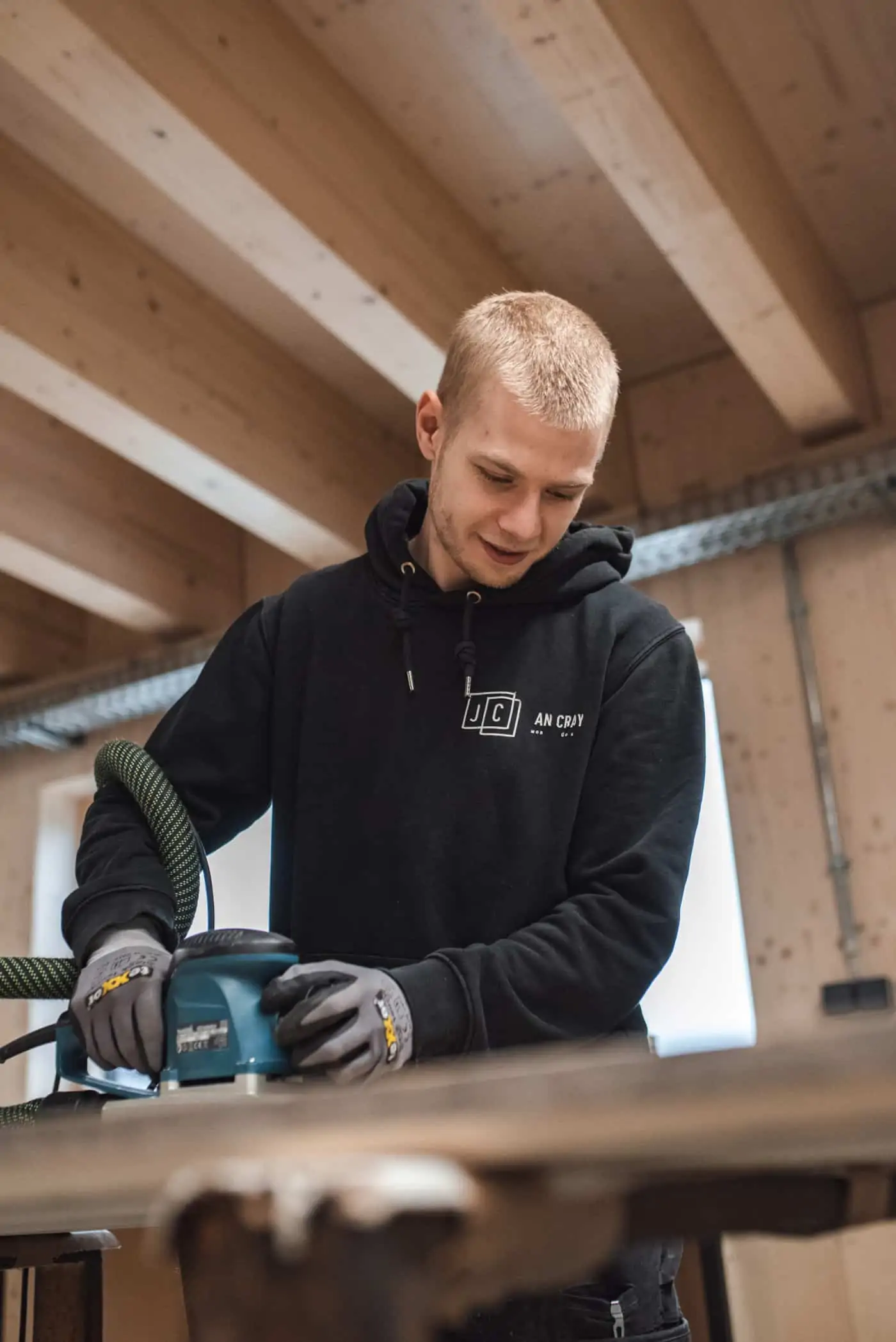 Mitarbeiter Timm beim schleifen einer recycelten Bauholzoberfläche.